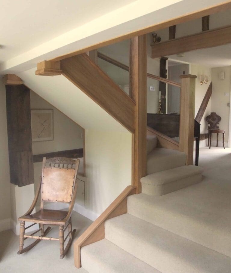 Oak staircase renovation with oversized newel posts and glass panels in balustrade