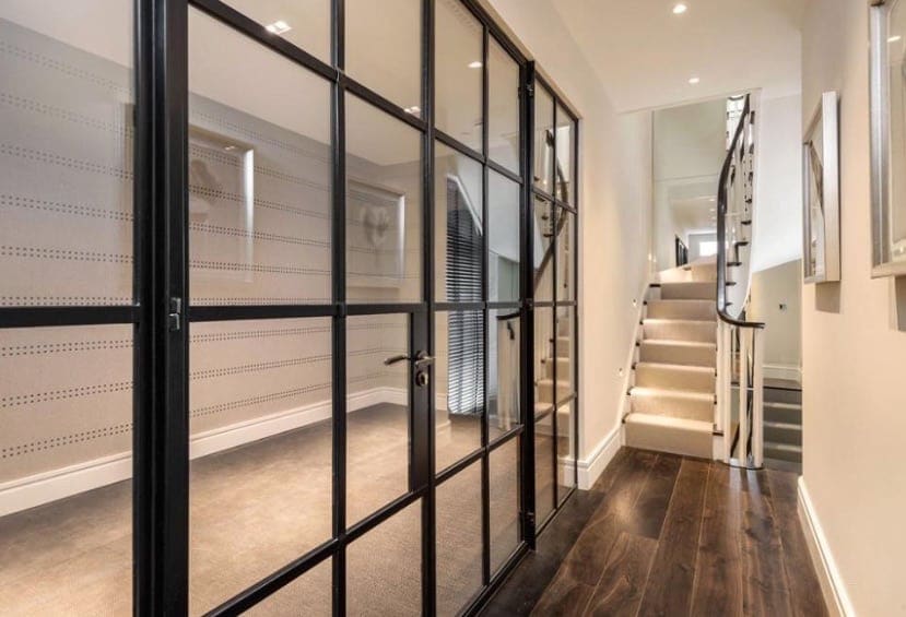 A modern hallway with black painted timber doors and stairs with sweeping continuous handrail & contrasting square white spindles
