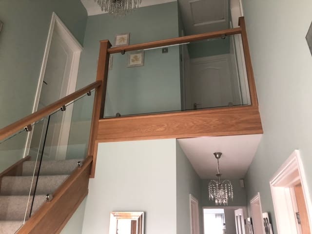 A winding oak staircase renovation in Brentwood with 10mm clamped glass panels brightens this Essex entrance hall.