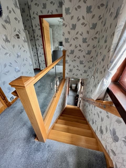 A dark staircase stuck between walls in Irvine is filled with light thanks to an Abbott-Wade glass & oak staircase renovation.