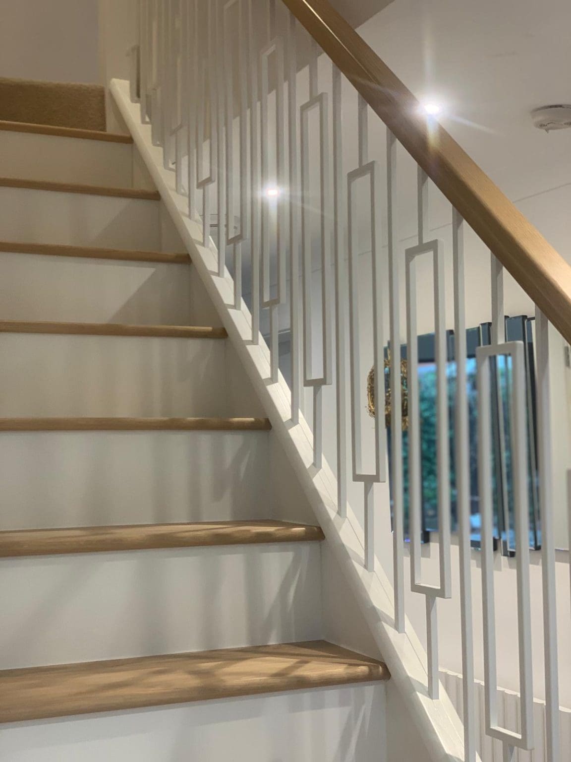 Our white metal Frame spindles pair with white newel posts and risers with contrasting oak treads & handrails create this light, bright staircase.