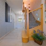 A bright & modern entrance hall in Clitheroe uses a glass balustrade in conjunction with the reflective properties of mirrors, floor tiles and walls to maximise the feeling of light and space.