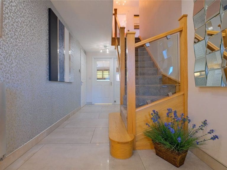 A bright & modern entrance hall in Clitheroe uses a glass balustrade in conjunction with the reflective properties of mirrors, floor tiles and walls to maximise the feeling of light and space.