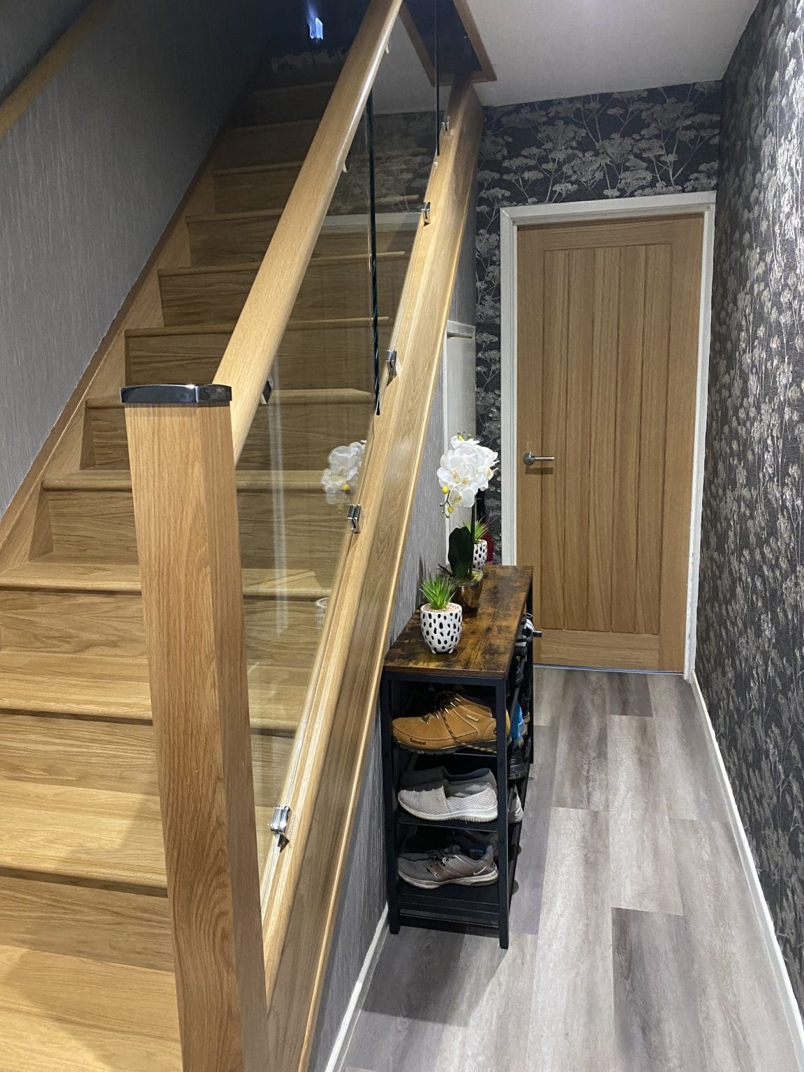 An oak & glass staircase renovation in Halifax with clamped glass with matching polished steel glass clamps and newel caps.