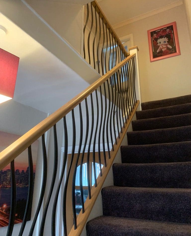 A cool combination of natural oak and white timber with Abbott-Wade Wave wrought iron effect spindles elevates this Middlesborough home.