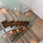 A mesmerising double cut string zigzag staircase in St Albans comprising a combination of walnut, stained oak & white timber with 15mm frameless glass balustrade.