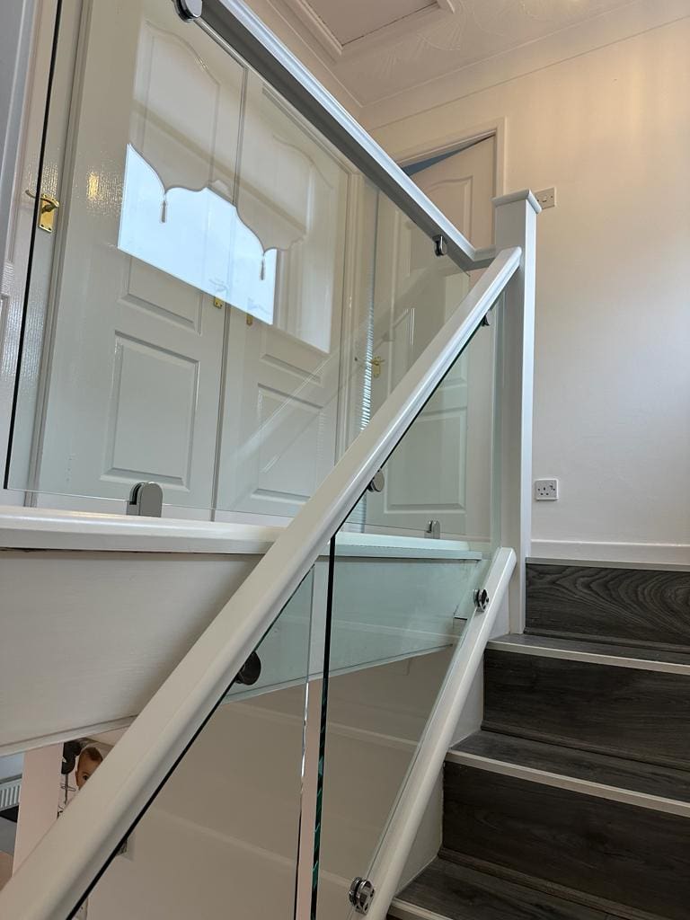 A white staircase renovation in St Helens with 10mm glass panels secured with stainless steel clamps.