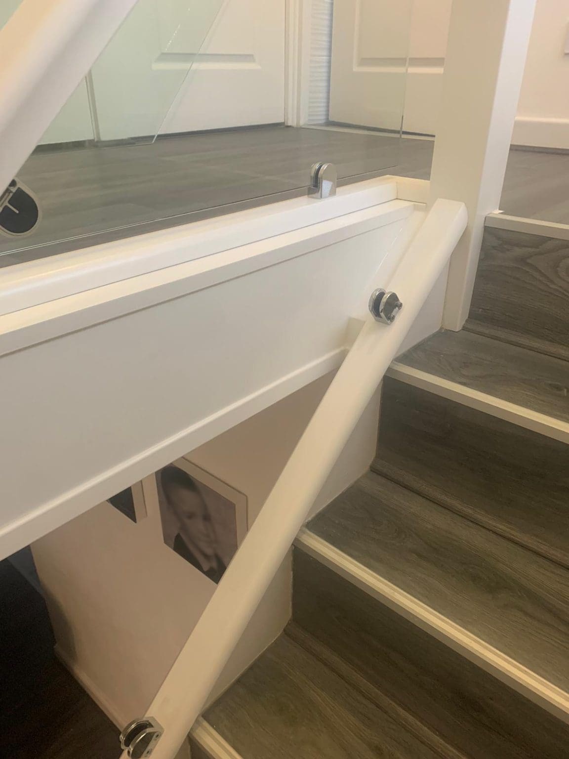 A white staircase renovation in St Helens with 10mm glass panels secured with stainless steel clamps.