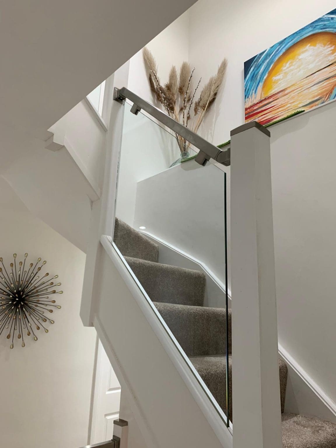 Existing white newel posts with brushed stainless steel and 10mm glass panels in Sutton transforms and brightens this South London home