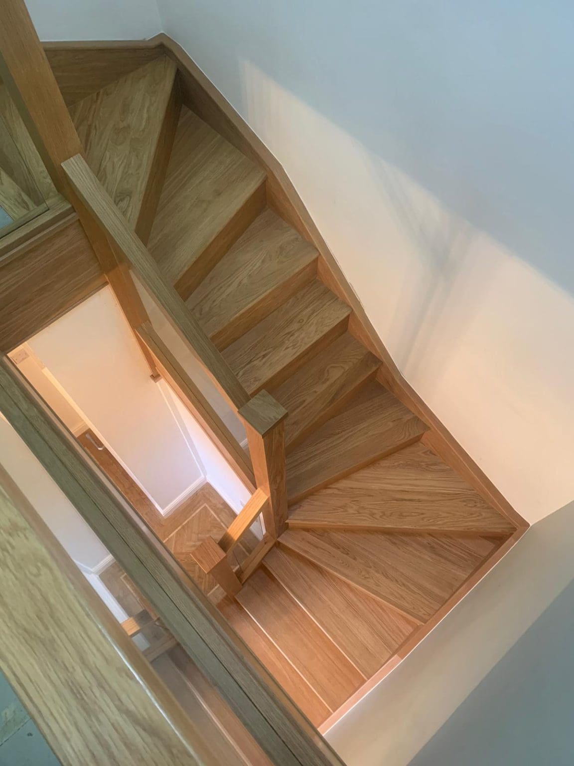 A modern glass staircase renovation with lots of clean straight edges and the warm hues of natural oak overlooking the Cumbrian coastline.